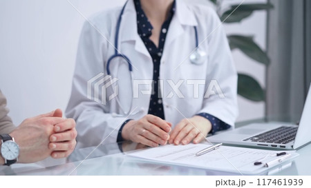 Doctor and patient are talking in clinic. Female physician is sitting and discussing test results with a senior man. Medicine and science 117461939