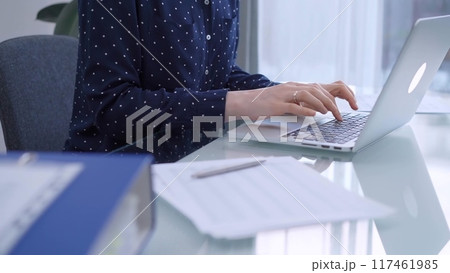Female accountant or businesswoman is typing on laptop computer on glass desk in the office. Business people concept 117461985