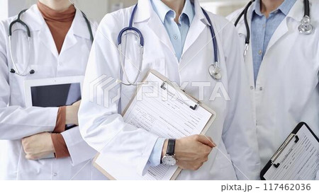Group of doctors wearing white coats and stethoscopes standing with clipboards. Medical team at work 117462036