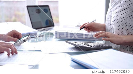 Business people, accountants or auditors reviewing financial data in office. Two professionals analyzing paper reports and using calculators. Audit and taxes 117462089