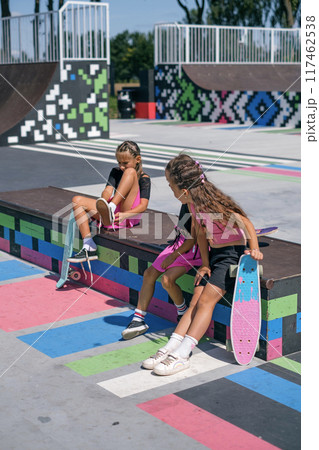 A girl changes shoes while sitting on a skatepark bench for comfortable skateboarding A girl changes shoes while sitting on a skatepark bench for comfortable skateboarding 117462538