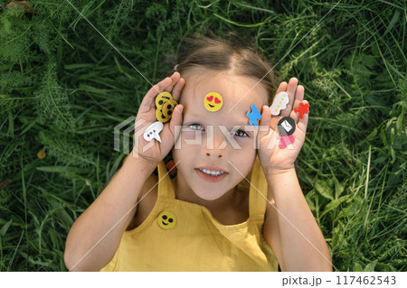 The girl holds in hands a web icon and emoji used to communicate on social networks The girl holds in hands a web icon and emoji used to communicate on social networks 117462543