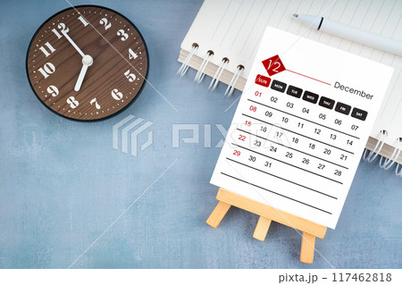 2024 December calendar page and wooden clock on blue wooden. 117462818