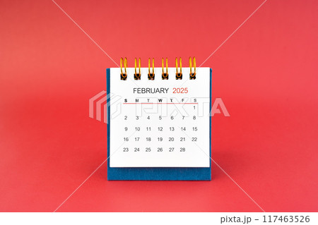 February 2025 white desk calendar on red background. 117463526