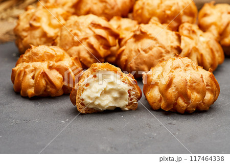 Delicious cream-filled profiteroles arranged on a dark slate surface, perfect for dessert lovers 117464338