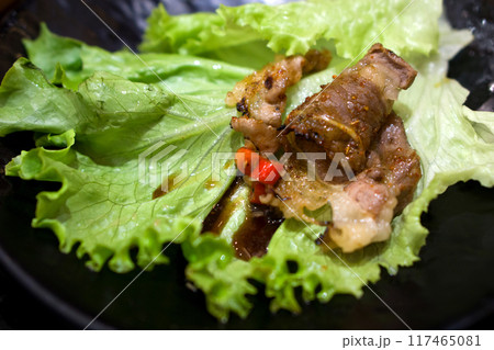 Grilled meat with spices and chili on fresh green lettuce. A delicious and spicy dish served on a dark plate. Grilled meat with spices and chili on fresh green lettuce. A delicious and spicy dish served on a dark plate. 117465081