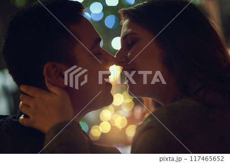 Date, kiss and couple at restaurant for engagement, anniversary or celebration with love. Bokeh, marriage and romance with partner embrace for happy people at night with relationship in dark 117465652