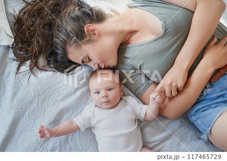 Kiss, mom and baby in bed at home for relax, rest and bonding together as family. Happy people, mother and boy infant in bedroom for embrace with love, support or security as parent in apartment 117465729