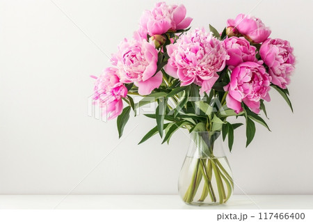 Bouquet of pink peonies in a glass vase on a white background 117466400