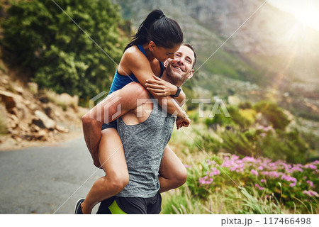 Happy couple, exercise and piggyback with smile in nature for marathon training, cardio workout or challenge. Sunshine, sports and man carrying woman on mountain for fitness, wellness or endurance 117466498