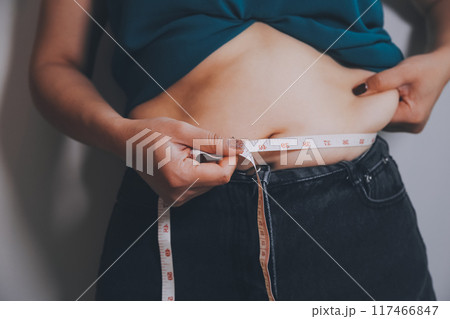 fat woman, fat belly, chubby, obese woman hand holding excessive belly fat with measure tape, woman diet lifestyle concept fat woman, fat belly, chubby, obese woman hand holding excessive belly fat with measure tape, woman diet lifestyle concept 117466847