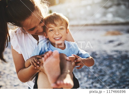 Mom, child and beach fun with smile, hug and laughing by the sea with love, care and bonding. Vacation, holiday and travel outdoor with parent and boy by the ocean with summer and trip together 117466896
