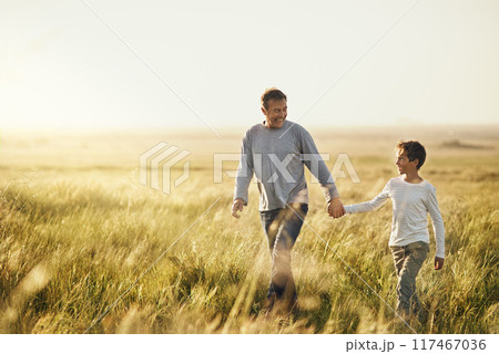 Holding hands, walking and father with child on farm at sunset for bonding together on vacation. Happy, nature and dad with boy kid on adventure, holiday or weekend trip in agriculture countryside. 117467036
