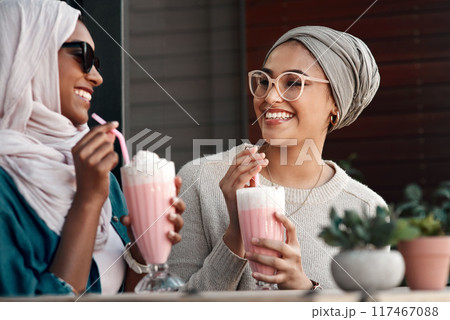 Muslim women, milkshake and happy in cafe with conversation, bonding or reunion for drinks. Islamic people, talking and relax with smile for memory, chat or story with dessert smoothie at coffee shop 117467088