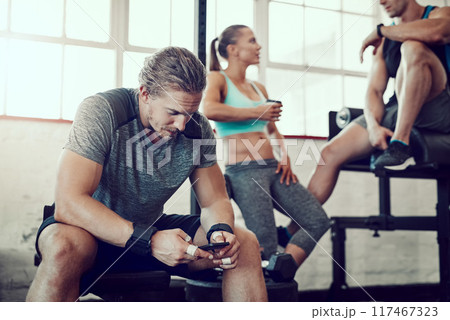 Man, fitness and typing with phone at gym for workout schedule, routine or browsing tips. Active male person scrolling on mobile smartphone for online tutorial, sports or exercise at health club 117467323
