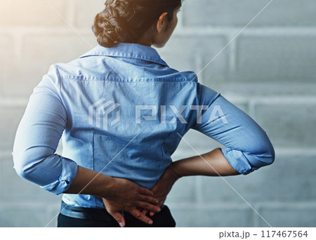 Business, woman and stress with back pain by brick wall for muscle fatigue, tension and work injury. Corporate, professional and female person with problem in health for strain, sore or ache in spine 117467564