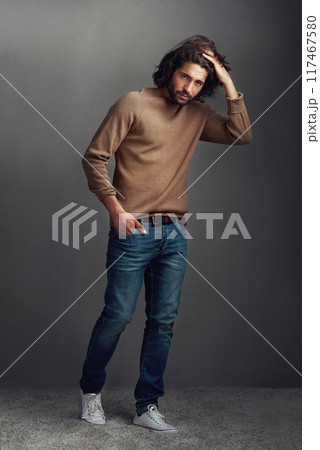 Serious, man and portrait with fashion in studio for elegant, style and comfortable winter jeans as clothes. Pride, male person and designer jersey, hairstyle or hand in pocket on grey background 117467580