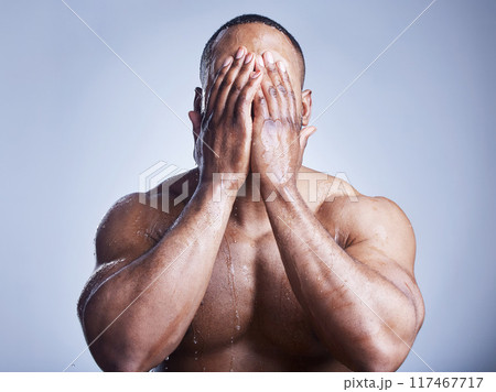 Black man, hands and water drop for washing face in studio, cleaning and hydration on blue background. Male person, liquid and skincare for facial treatment, fresh and cosmetics for grooming routine 117467717