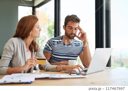 Couple, credit card and laptop at table for budget in morning with stress for online payment in house. People, banking and finance with bills, taxes and monthly payments for debt in apartment. 117467997