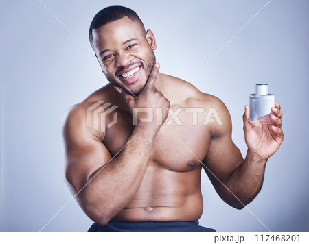 Black man, cologne and bottle in studio portrait, body care and perfume spray on blue background. Person, deodorant and container for aroma or fresh scent, clean smell and shirtless for fragrance Black man, cologne and bottle in studio portrait, body care and perfume spray on blue background. Person, deodorant and container for aroma or fresh scent, clean smell and shirtless for fragrance 117468201