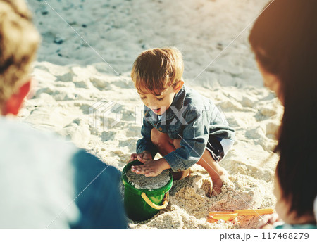 Play, beach and boy with parents, sand and sunshine with vacation, getaway trip and bonding together. Happy family, mother and father with son, seaside and toys with holiday, summer and weekend break 117468279