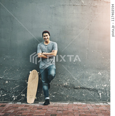 Fashion, skateboard and portrait of man in city with trendy style, cool outfit and crossed arms outdoors. Happy, confidence and person on wall background for skateboarding, weekend fun and holiday 117468594
