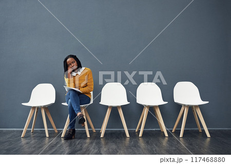 Wait, bored and black woman for recruitment, hiring or meeting for interview in office. Chairs, tired and female person as candidate of human resources, exhausted or impatient with paper in workplace 117468880