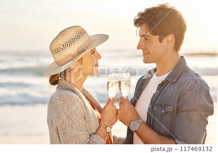 Sunset, drink and couple on beach with champagne on vacation with happiness at celebration in France. Marriage, holiday or people relax at sea together with wine, cocktail and cheers to date at ocean 117469132