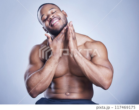 Black man, happy and skincare in studio with cosmetics for smooth skin, facial treatment or morning routine. Model, person and topless with smile for wellness, self care or hygiene on blue background 117469175