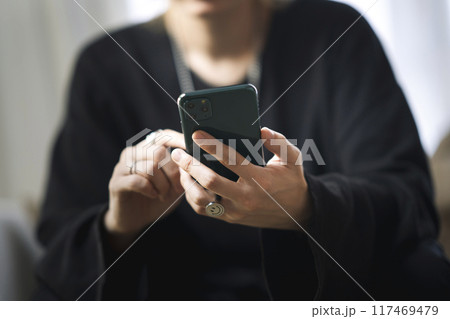 スマートホンを操作する若い男性の手元 117469479