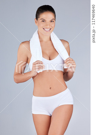 Portrait, woman or athlete body smiling for health, fitness or workout in grey studio background. Wellness, female person and towel happy for training, weight loss or exercise in active underwear 117469640