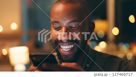 Face, laughing and phone with black man in home at night for communication, meme or networking. Comedy, funny and humor with person reading text message on mobile in apartment for social media 117469717