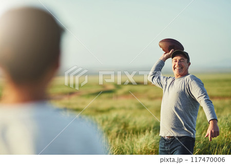 Kid, dad and football with teaching in nature for outdoor sports, adventure and child development. Smile, man and throw with son on field for exercise, practice and bonding on fathers day in Texas 117470006