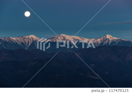 竜ヶ岳から見る西に傾いた満月と朝焼けの白峰三山 117470125