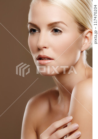 Woman, glow and skincare in studio for beauty, foundation and makeup treatment on brown background. Female person, dermatology and confidence for shine, smooth skin and facial wellness for cosmetics 117470204