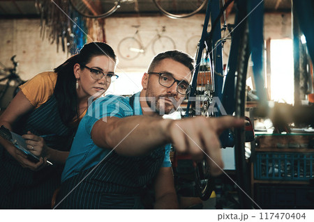 Bicycle technician, working and repair in shop with chains, frame and tools for maintenance or cycling. Man, bike and mechanic in workshop as teamwork for gear, inspection and safety with glasses 117470404