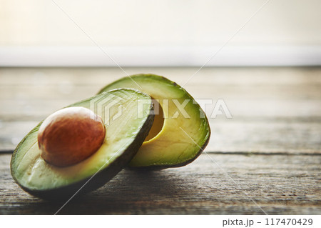 Closeup, half and avocado on wood table for nutrition with cooking, clean eating and ingredient for salad. Natural product, food and green fruit for healthy vegan diet with wellness snack and seed Closeup, half and avocado on wood table for nutrition with cooking, clean eating and ingredient for salad. Natural product, food and green fruit for healthy vegan diet with wellness snack and seed 117470429