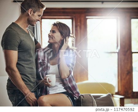 Couple, coffee and home with embrace, living room and smile in marriage, relax and peace in break and morning. House, man and woman on sofa, together and rest in lounge bonding and hug in weekend 117470592