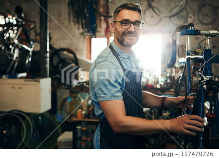 Happy man, portrait or mechanic with bicycle in small business for repair, fix or maintenance. Male person, cycle technician or bike engineer working on cycling vehicle, gears or hardware at workshop Happy man, portrait or mechanic with bicycle in small business for repair, fix or maintenance. Male person, cycle technician or bike engineer working on cycling vehicle, gears or hardware at workshop 117470726
