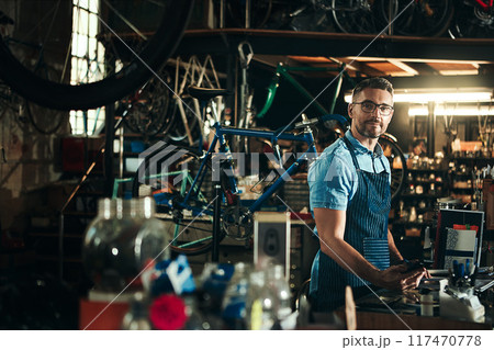 Man, portrait and bicycle mechanic with tools in small business for fix, repair or maintenance. Young male person, cycle engineer or bike technician with equipment for job or career at workshop 117470778