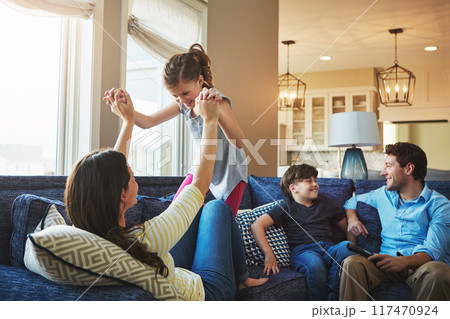 Happy, playing and kids with parents on sofa in home relaxing with care, fun and love together. Smile, bonding and girl child with mom, brother and dad sitting on couch in living room at family house 117470924