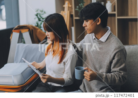 Young Asian couple relocating to a new house, joyfully packing and unpacking belongings. Expertise in moving, packing, togetherness, and creating a new home together. 117472401