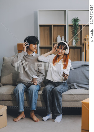 Asian Female discussing new project with male colleague. Young woman talking with young Asian man with financial on sofa in home office Asian Female discussing new project with male colleague. Young woman talking with young Asian man with financial on sofa in home office 117472434