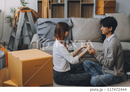 Asian Female discussing new project with male colleague. Young woman talking with young Asian man with financial on sofa in home office 117472444