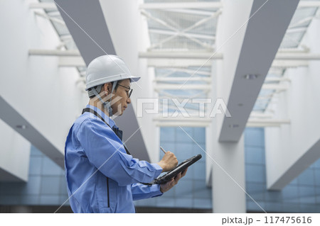 タブレットに入力する作業服姿の男性 ビルメンテナンス・施工管理・点検・調査 イメージ タブレットに入力する作業服姿の男性 ビルメンテナンス・施工管理・点検・調査 イメージ 117475616