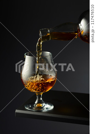 Cognac or brandy being poured into a glass. Cognac or brandy being poured into a glass. 117476510