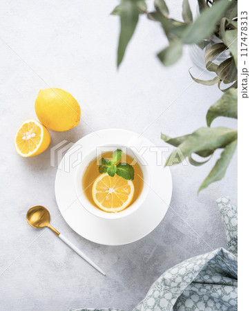 Herbal tea with lemon and mint in a white cup on a light background with eucalyptus branches Herbal tea with lemon and mint in a white cup on a light background with eucalyptus branches 117478313