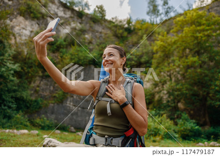 A Joyful Hiker Happily Taking a Fun Selfie While Delightedly Enjoying the Stunning Beauty of Nature A Joyful Hiker Happily Taking a Fun Selfie While Delightedly Enjoying the Stunning Beauty of Nature 117479187