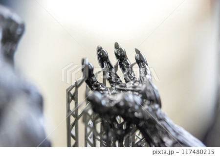 Model of hand printed on a 3D printer from black rubber, close-up. Part of an object created on a 3D printer from hardened rubber under the influence of ultraviolet light. SLA 3D printing technology. Model of hand printed on a 3D printer from black rubber, close-up. Part of an object created on a 3D printer from hardened rubber under the influence of ultraviolet light. SLA 3D printing technology. 117480215