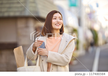 ハーフコートを着て買い物に行くミドルの女性 117480384